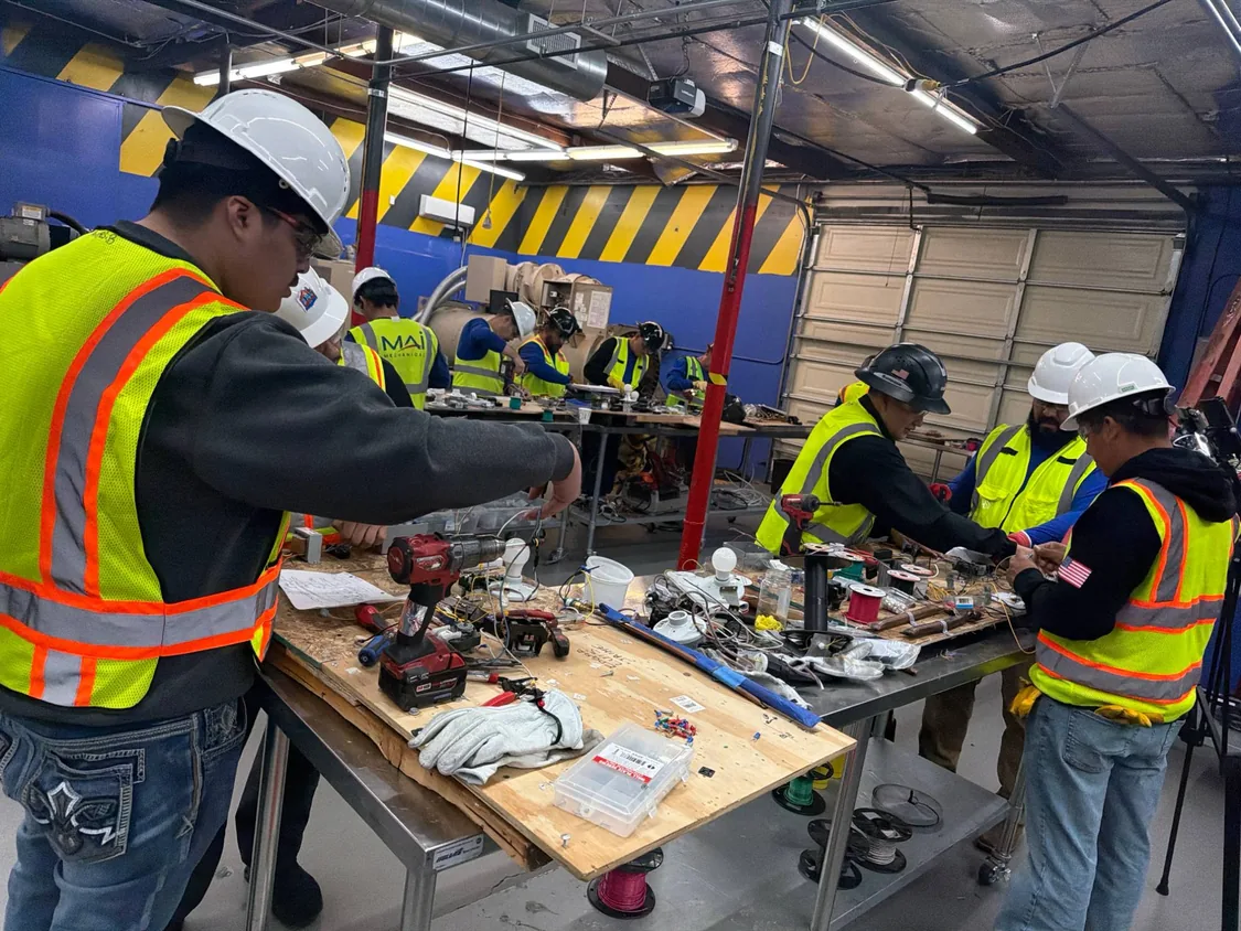 Varios grupos de alumnos trabajando en las mesas del taller con taladros y cableado
