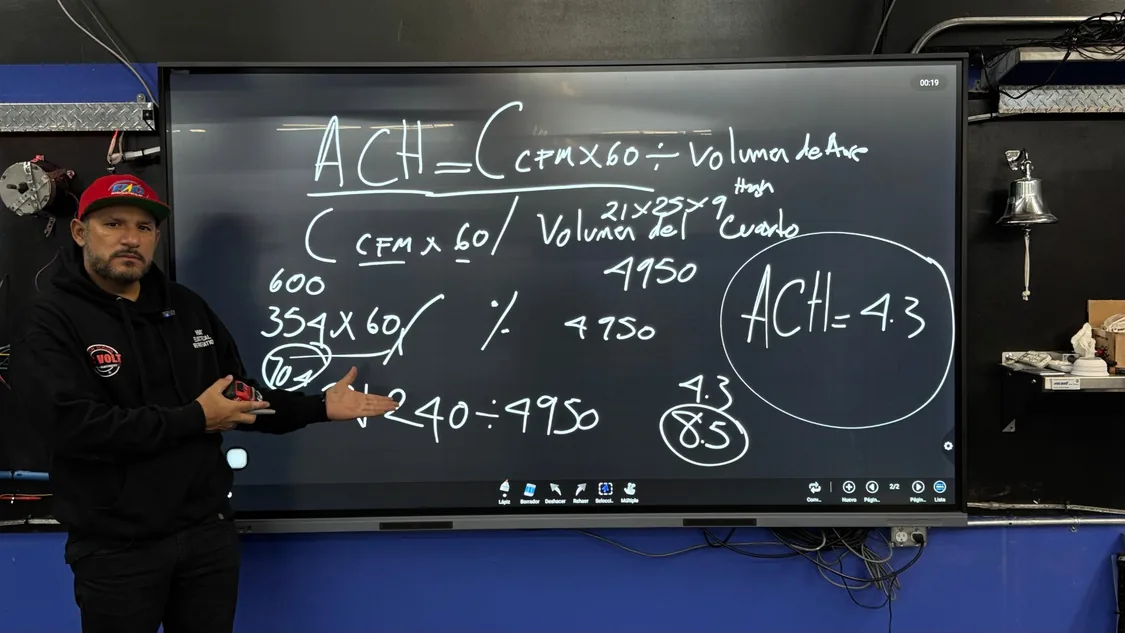 Instructor explicando la fórmula de cambios de aire por hora con un ejercicio resuelto