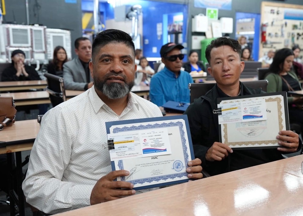 Dos estudiantes mostrando sus certificados en el salón